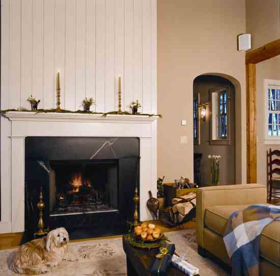 The home’s wood-burning fireplace warms the open living room in less than an hour on a wintry morning. Its soapstone surround stores radiant heat, much appreciated by Marguerite, who curls up on an antique rug from Michele’s childhood home.